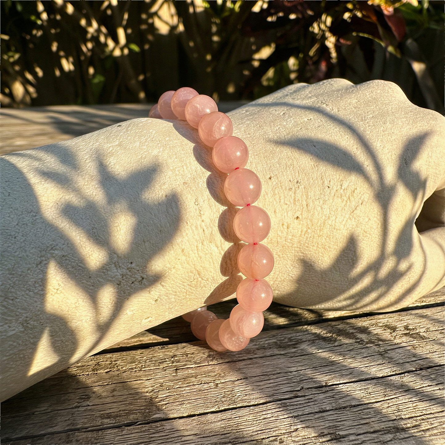 Madagascar rose quartz stretchy cord bracelet worn on wrist outdoors in warm daylight, serene natural setting