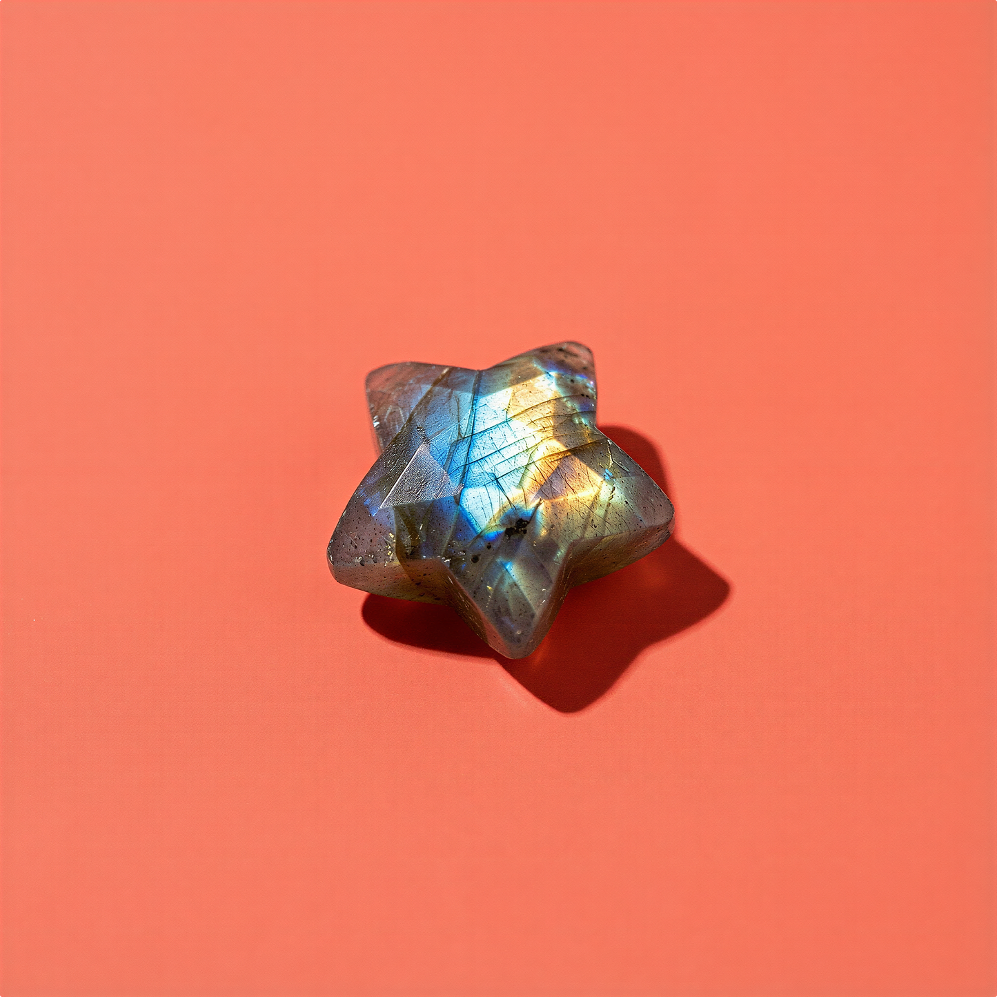 Faceted labradorite star briolette bead against bold saturated backdrop, highlighting iridescent flashes and sculptural sparkle