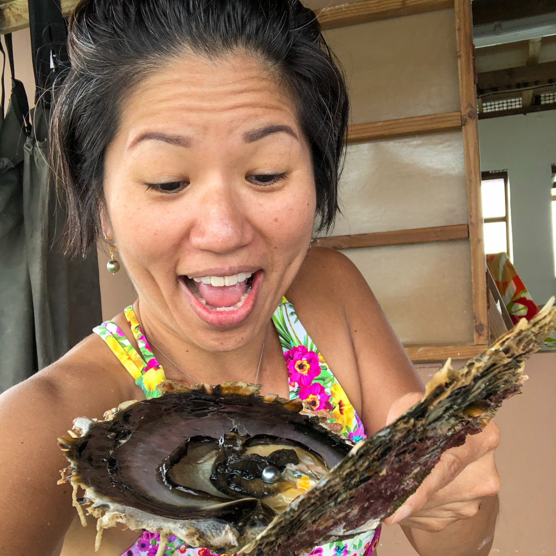 Jamie Yoshida holding an open black-lipped oyster with a Tahitian pearl inside