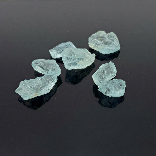 Raw aquamarine crystal specimen with refined clarity, natural blue tones enhanced on a clean neutral surface