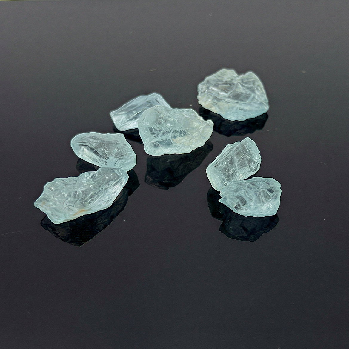 Raw aquamarine crystal specimen with refined clarity, natural blue tones enhanced on a clean neutral surface