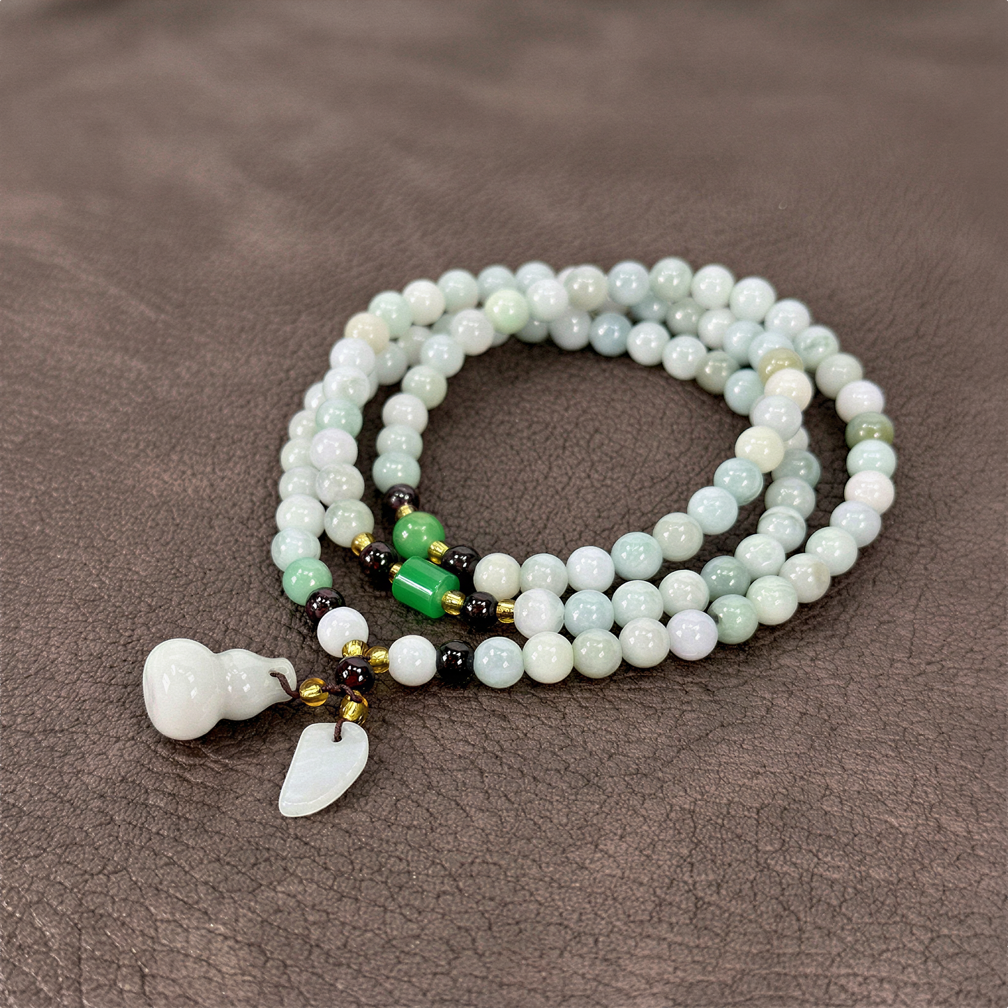 Jade triple wrap stretchy cord necklace with prosperity charms styled on bold, saturated color backdrop