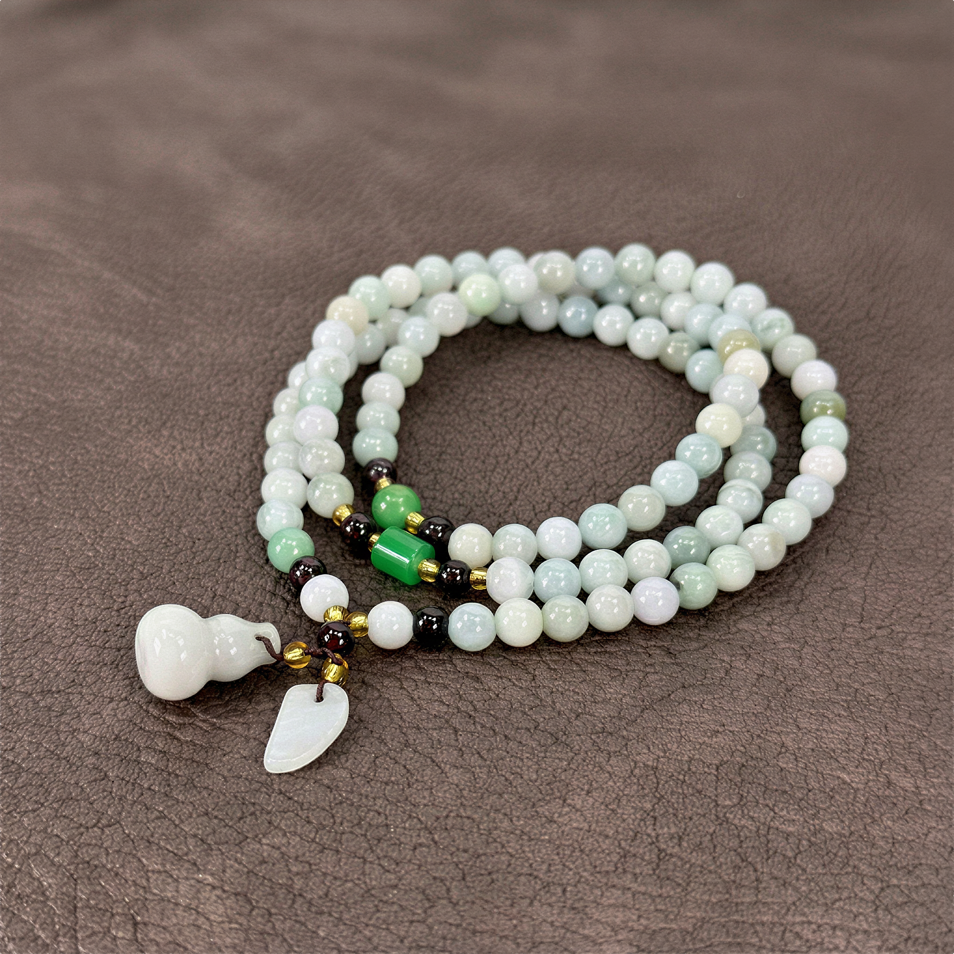 Jade triple wrap stretchy cord necklace with prosperity charms styled on bold, saturated color backdrop