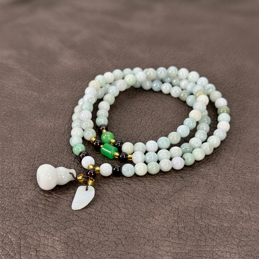 Jade triple wrap stretchy cord necklace with prosperity charms styled on bold, saturated color backdrop