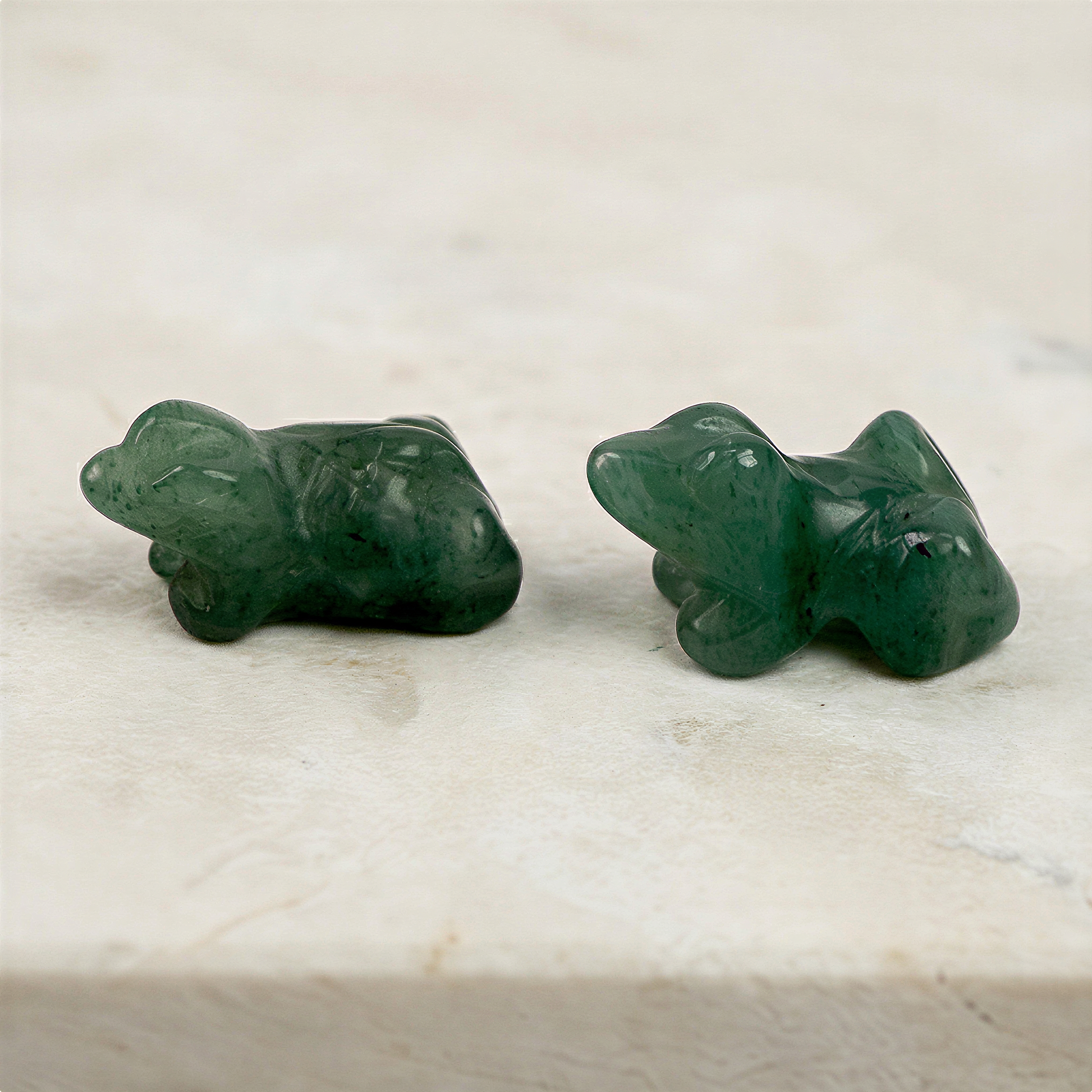 Polished aventurine carved frog beads displayed on neutral surface with enhanced clarity, rich green tones, and refined lighting