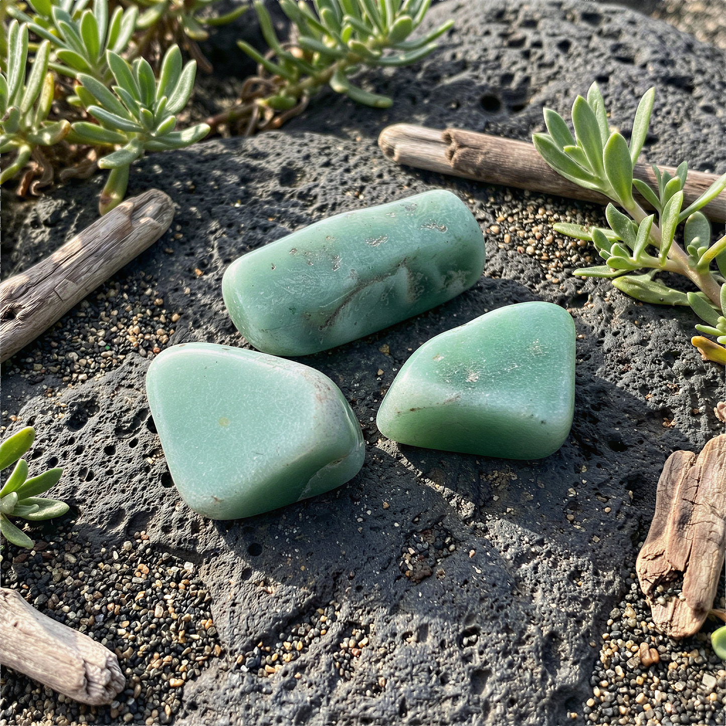 Three green aventurine tumbled stones in soft natural light on earthy surface inspired by Hawaiian landscapes