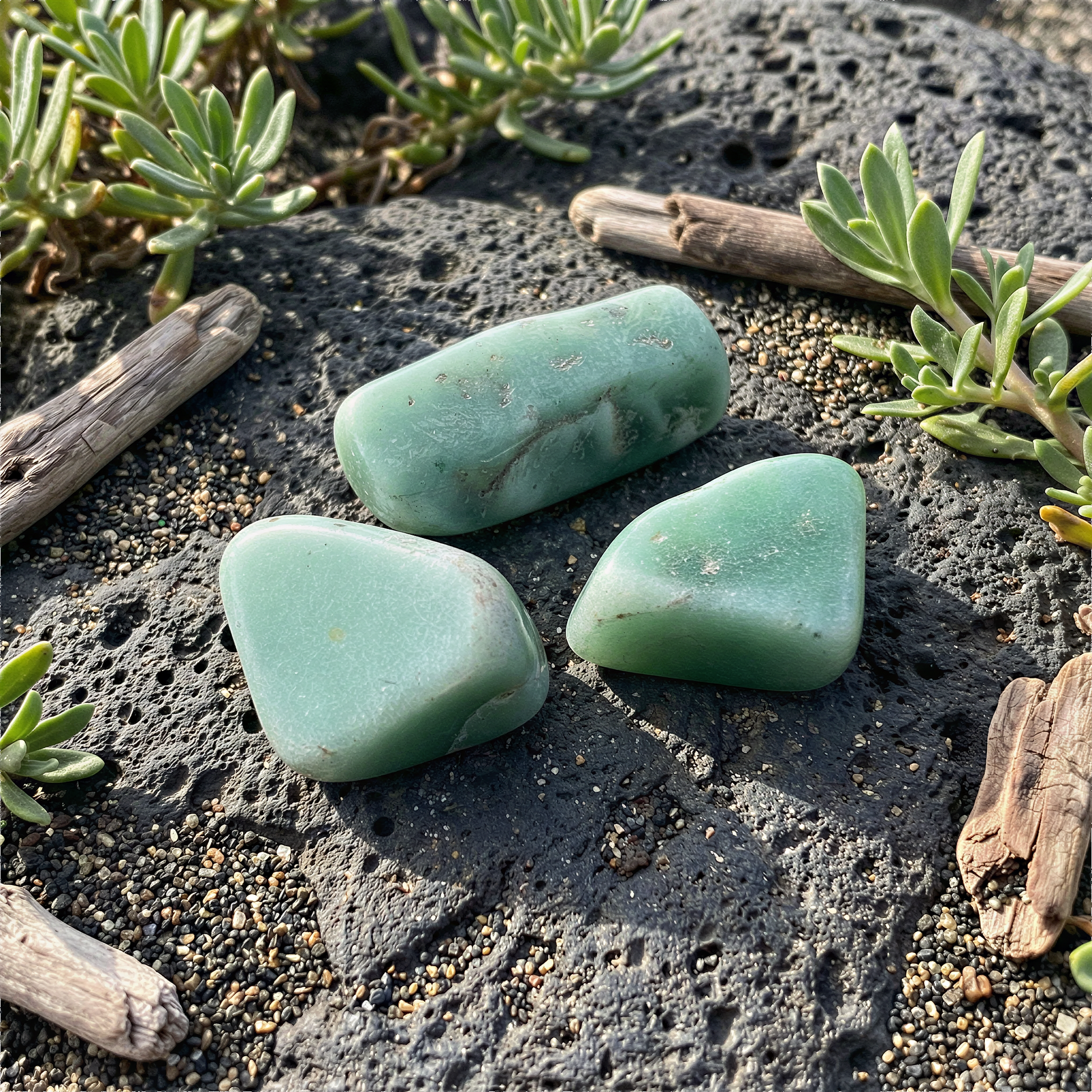 Three green aventurine tumbled stones in soft natural light on earthy surface inspired by Hawaiian landscapes