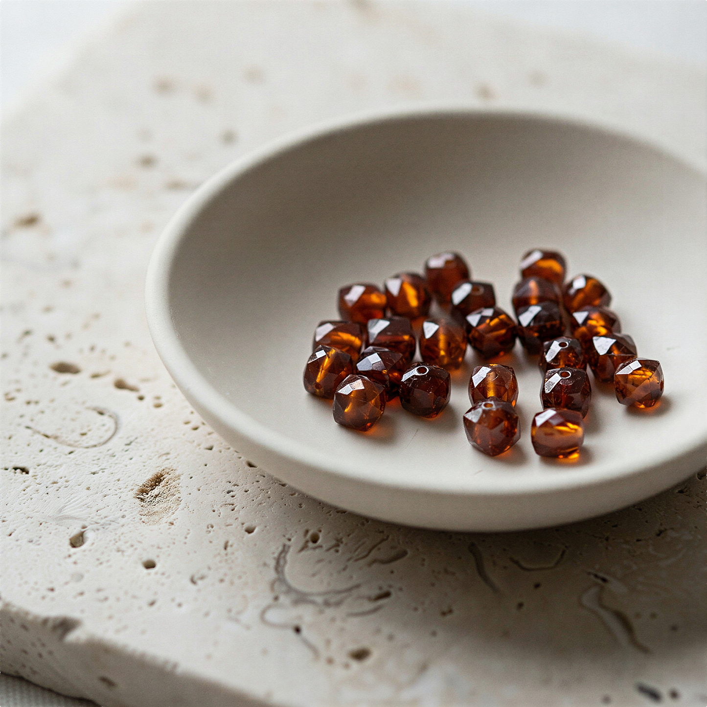 Large-facet hessonite garnet bead resting on natural stone surface in soft, diffused daylight
