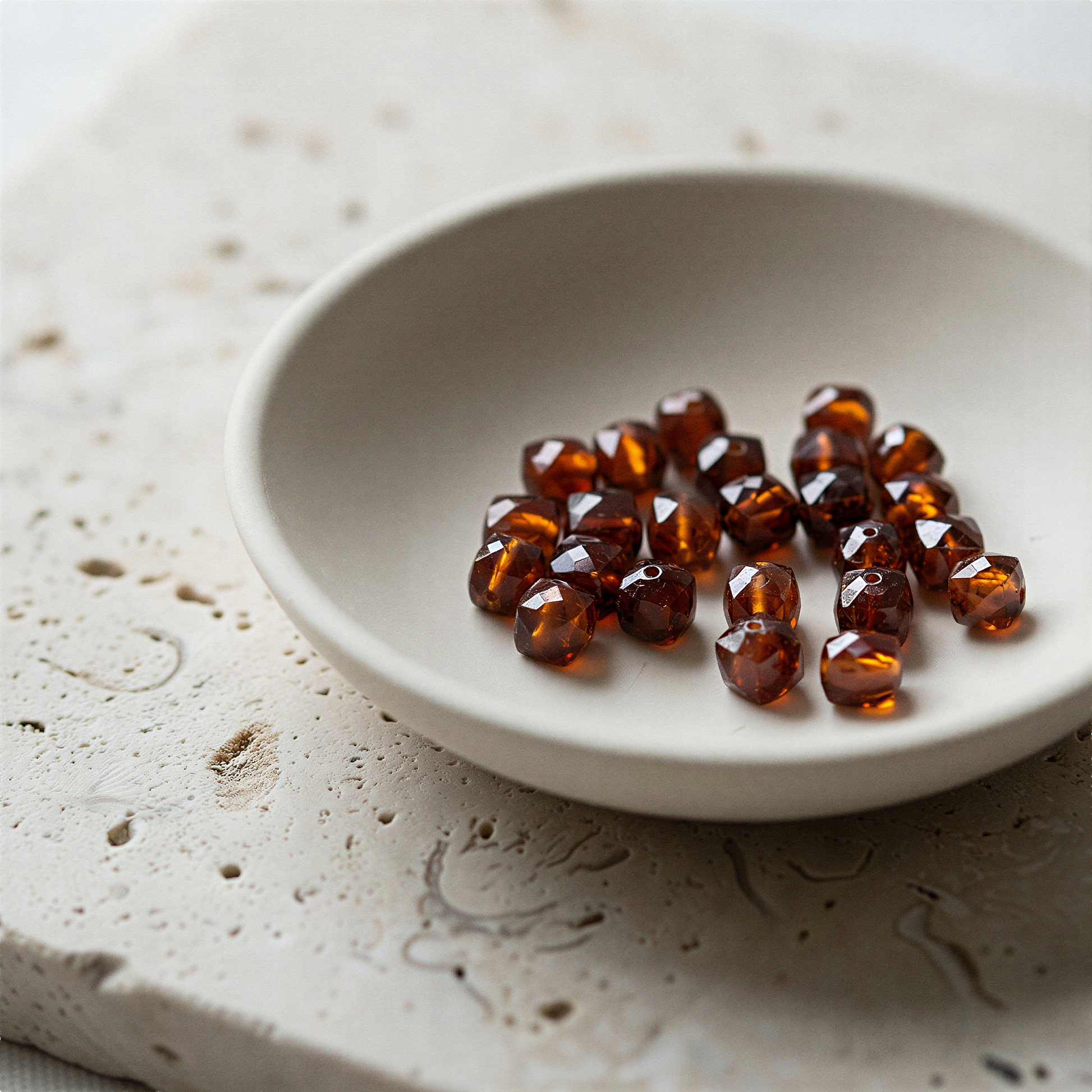 Large-facet hessonite garnet bead resting on natural stone surface in soft, diffused daylight