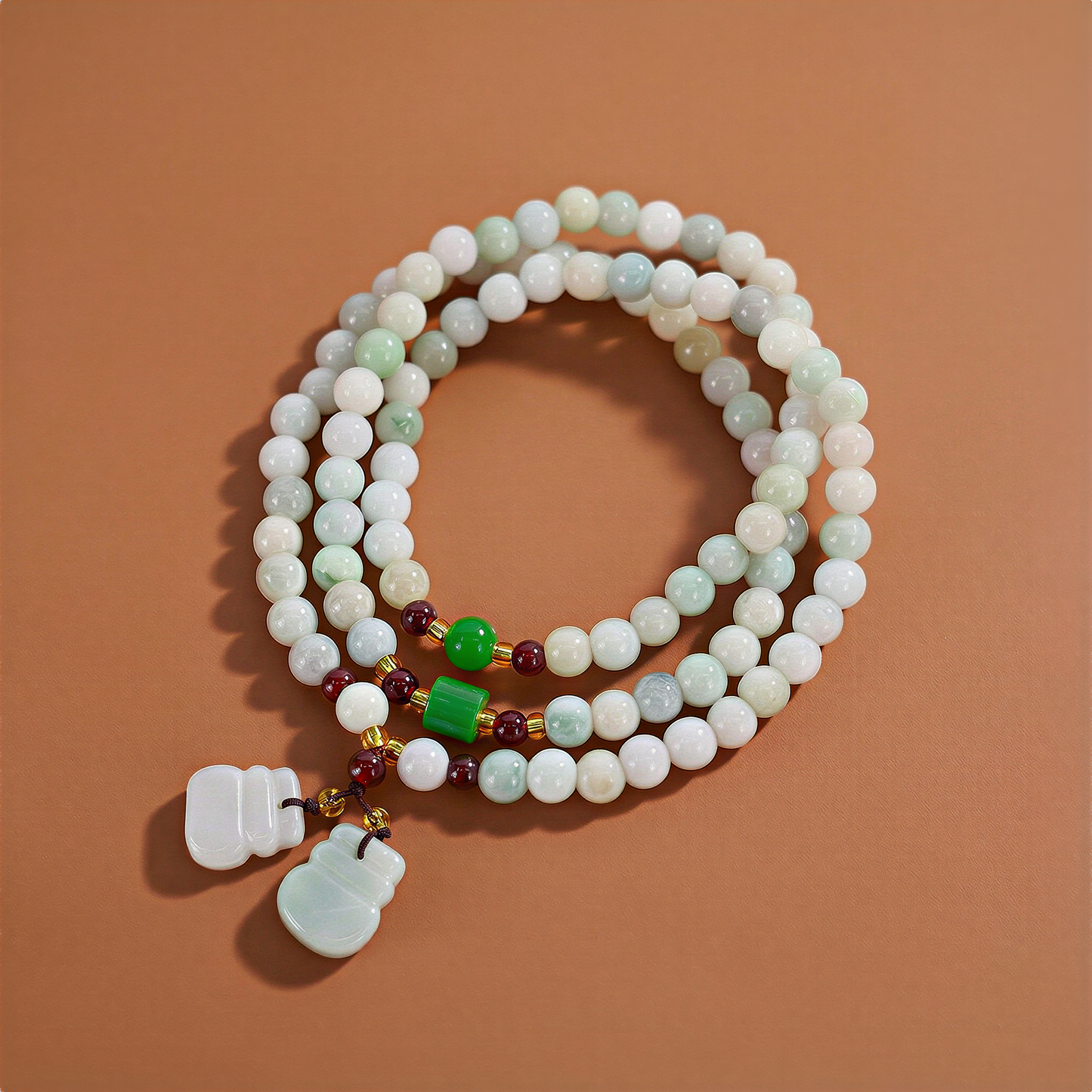 Triple-wrap jade bead necklace with delicate prosperity charms, arranged against a warm chocolate-brown backdrop under soft, inviting studio light.