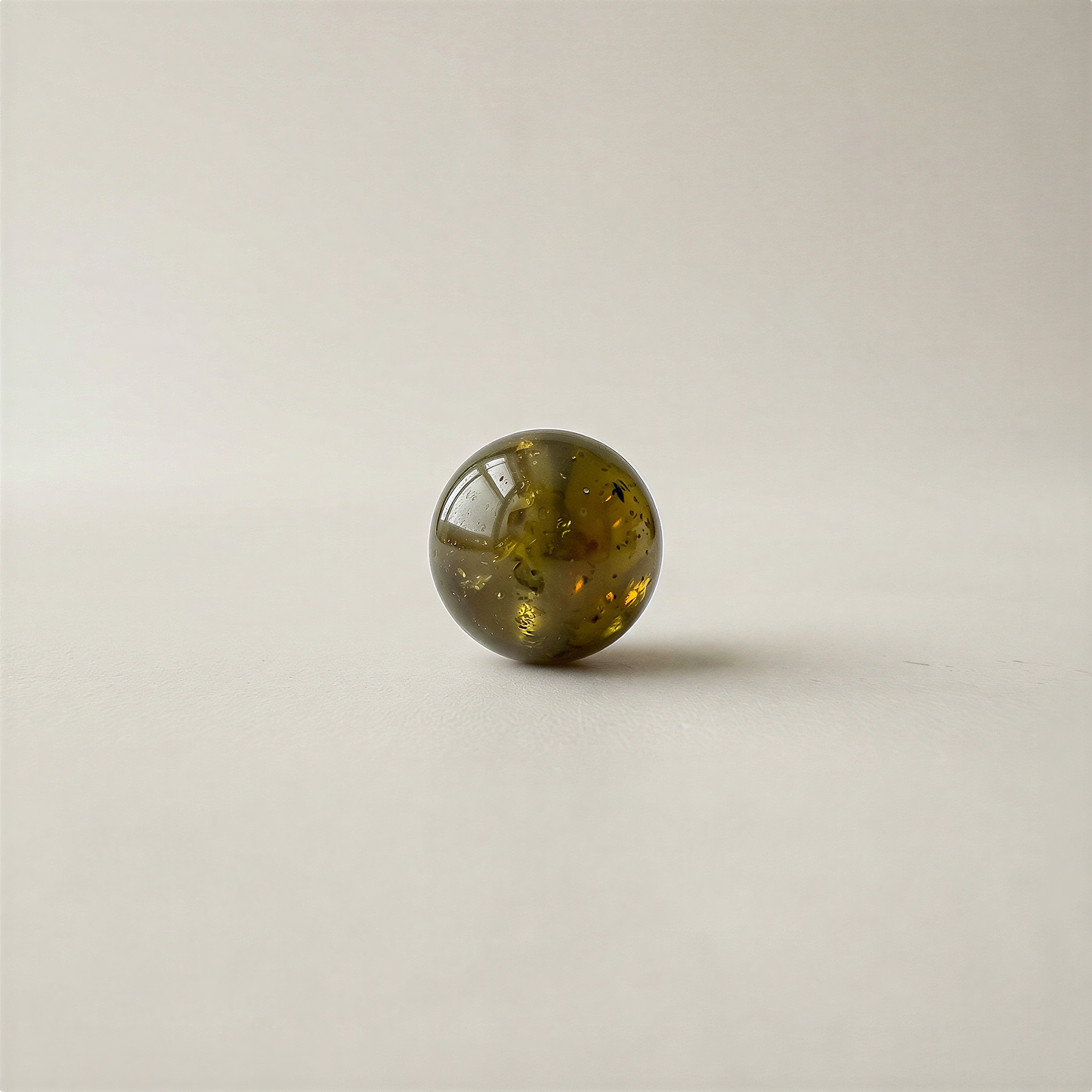Single smooth green garnet bead on neutral surface with soft lighting, enhanced clarity and natural color.