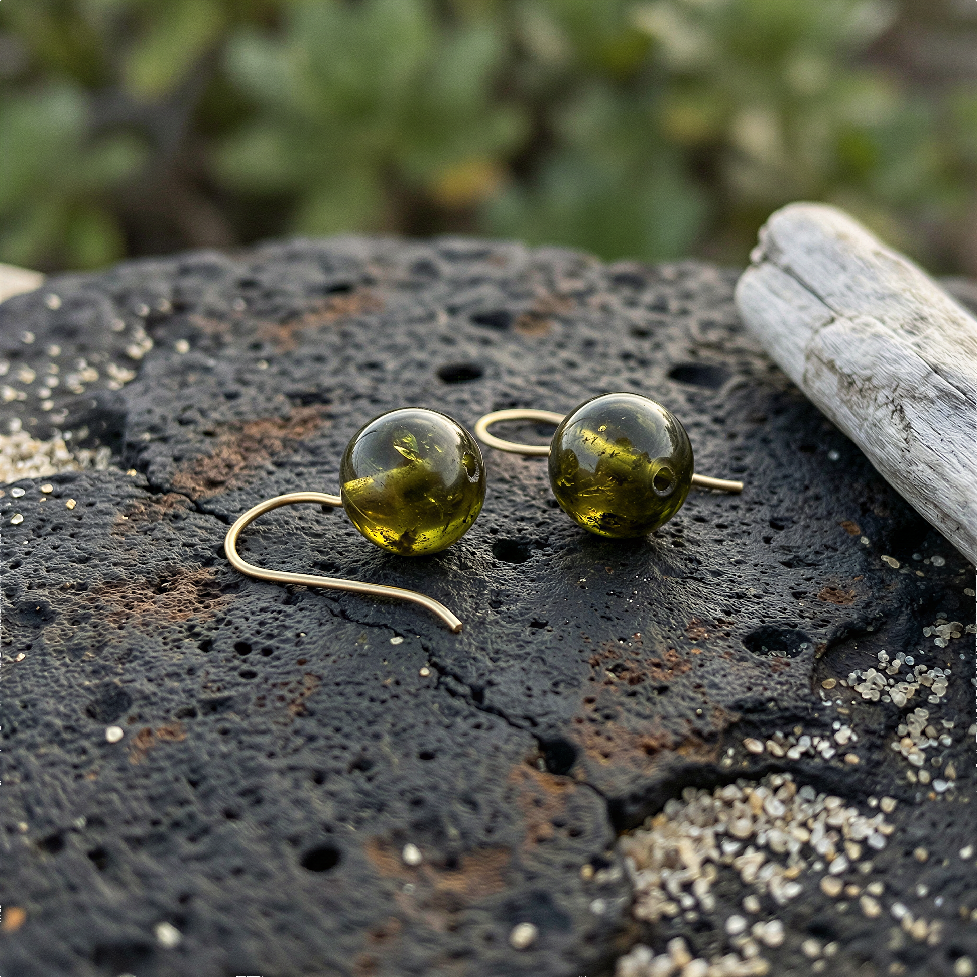 Single 10mm green garnet bead resting on volcanic sand with tropical leaves in soft natural light