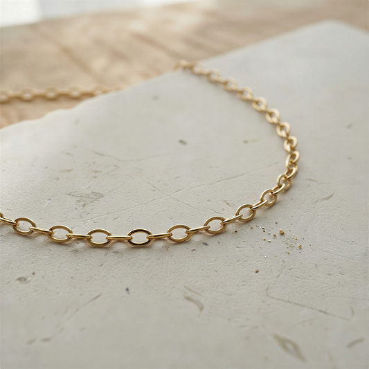 Silver and gold oval cable chain resting on natural stone with soft daylight