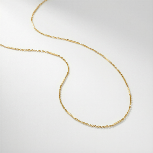 Gold filled long chain jewelry laid in clean profile on seamless white studio background