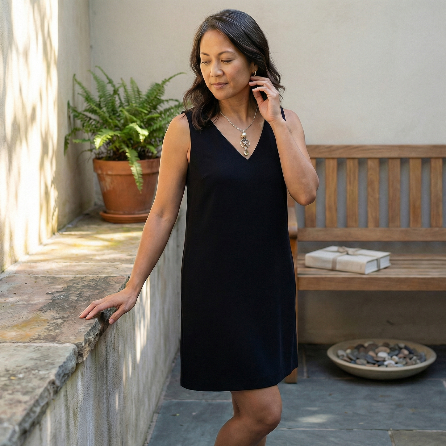 Gold pearl pendant with starfish charm and teardrop citrine on a short chain, resting at the collarbone in soft, warm light