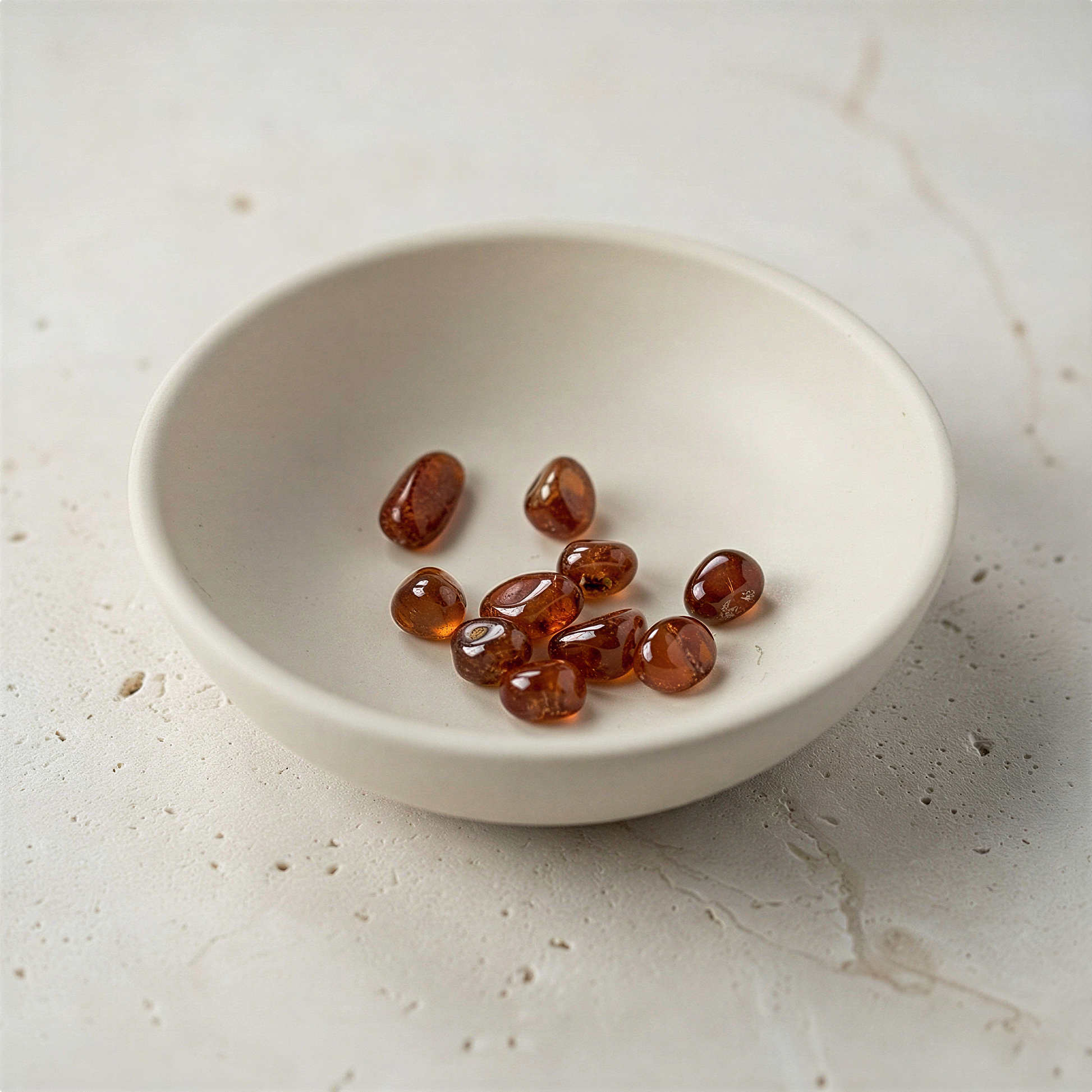 Small hessonite garnet nugget resting on natural stone surface with soft ambient light, understated and serene.