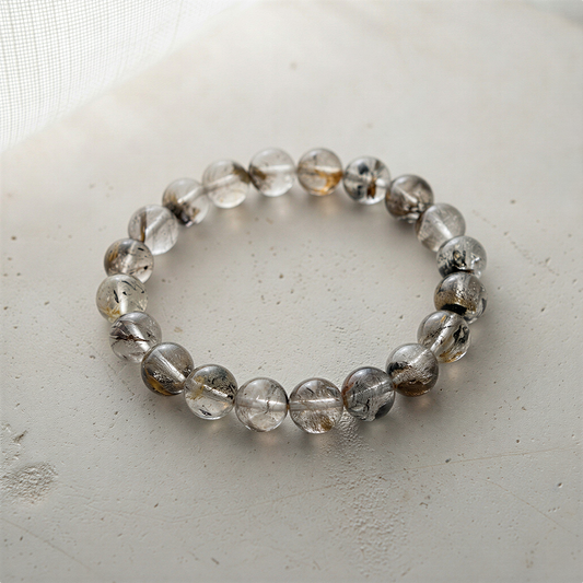 Black Forest quartz bead bracelet resting on mossy stone with soft forest light and earthy textures