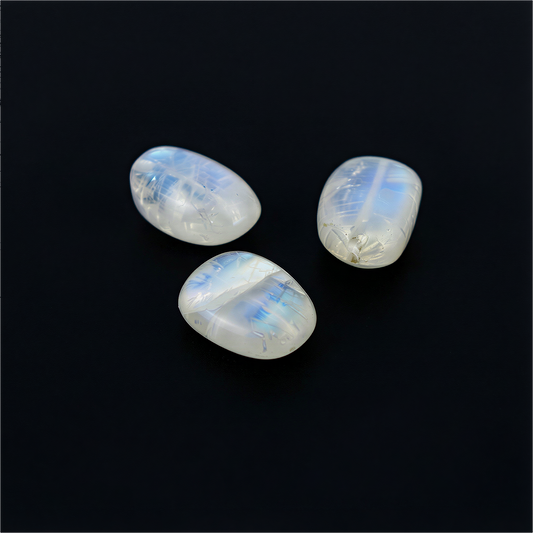 Single rainbow moonstone nugget bead floating against a deep black background, glowing with soft blue flashes and natural translucent texture