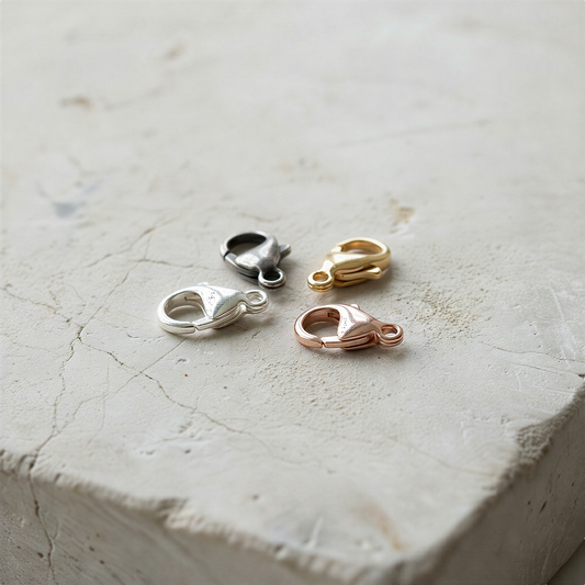 9mm oval lobster clasp in silver tones resting on stone with soft natural light and moss accents