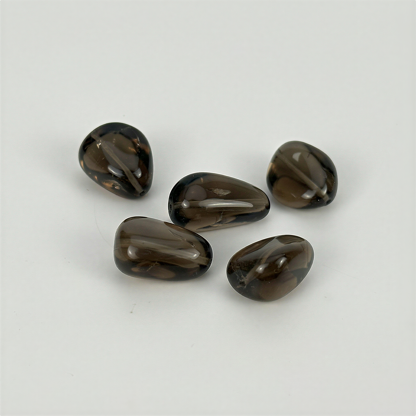 Smoky quartz tumbled nugget bead on neutral linen surface with soft diffused light, refined clarity.