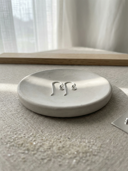 Delicate earwires on a hand‑poured clay disk with linen‑filtered morning light.