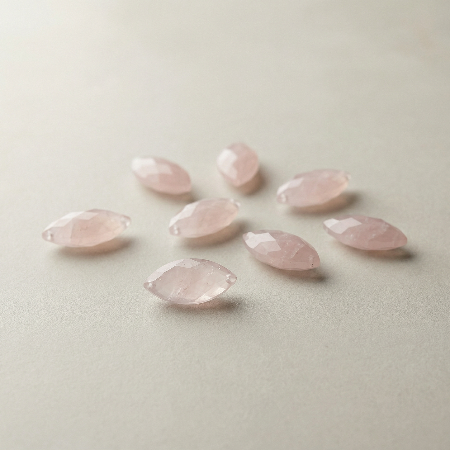 Faceted rose quartz marquise bead resting on soft neutral linen with diffused light and serene, balanced styling