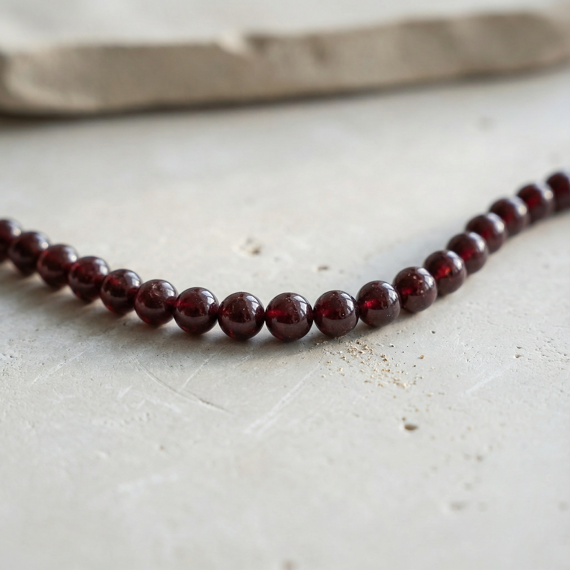 Star garnet smooth round bead strand resting on natural linen with soft, earthy light and understated elegance