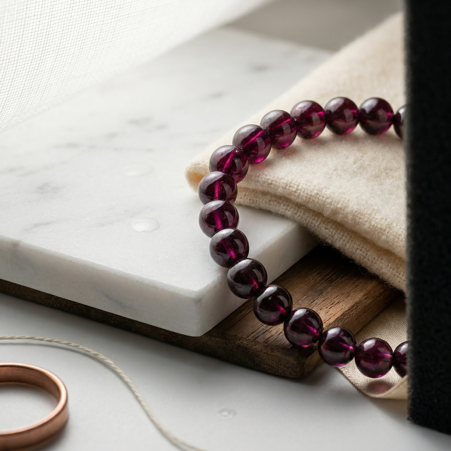 Rhodolite garnet bracelet on honed marble edge with cashmere and walnut.