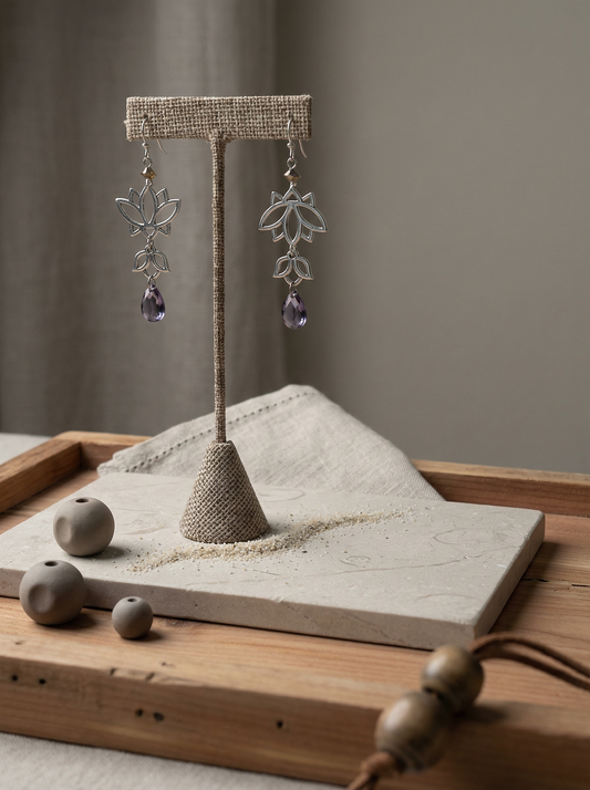 Lotus chandelier earrings on honed limestone with linen, clay beads, and cedar tray.