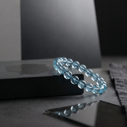 Blue topaz bead bracelet on dark cement plinth with soft rim light and smoked glass
