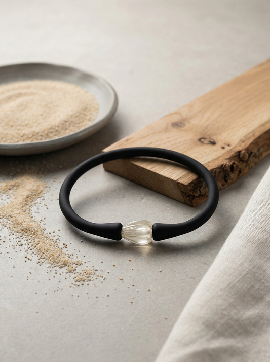 Matte silicone bracelet on limestone with clay dish, oak strip, linen, and scattered sand.